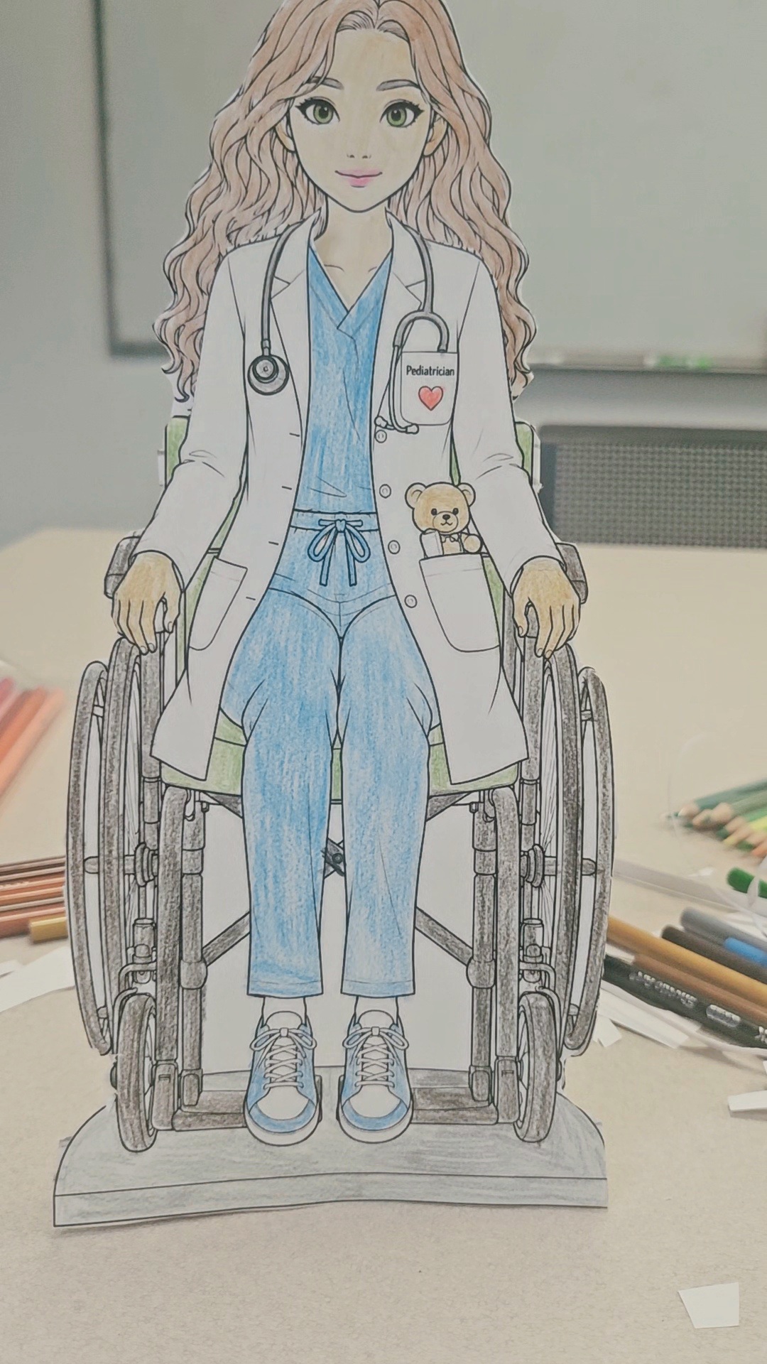 A paper-doll character using a wheelchair dressed as a pediatrician