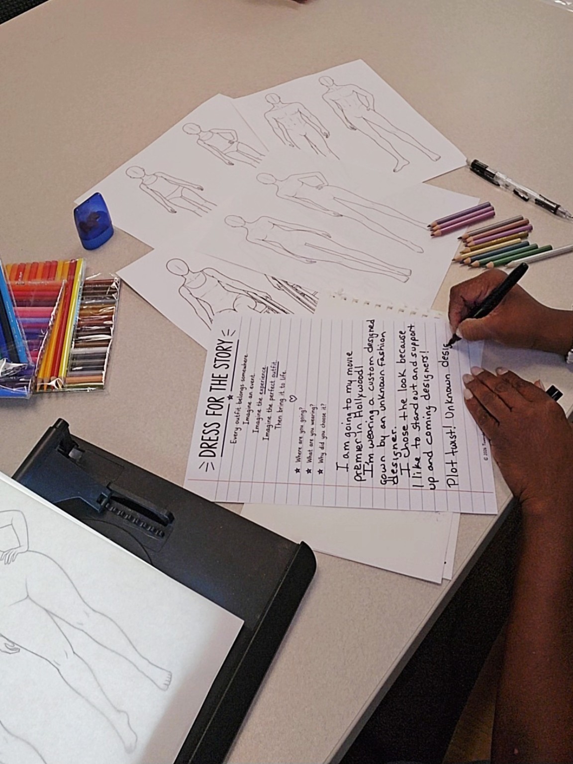 Tuwanda writing a StyleStory beside fashion figure templates